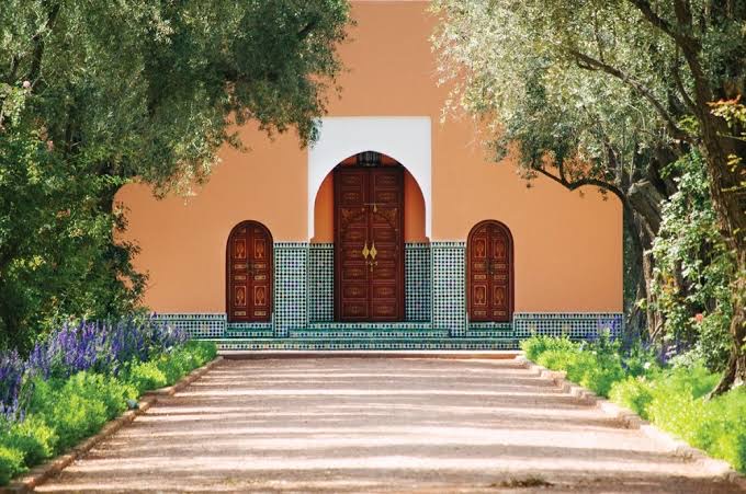 A small garden pavilion among orange trees at the end of a wide gravel walk.