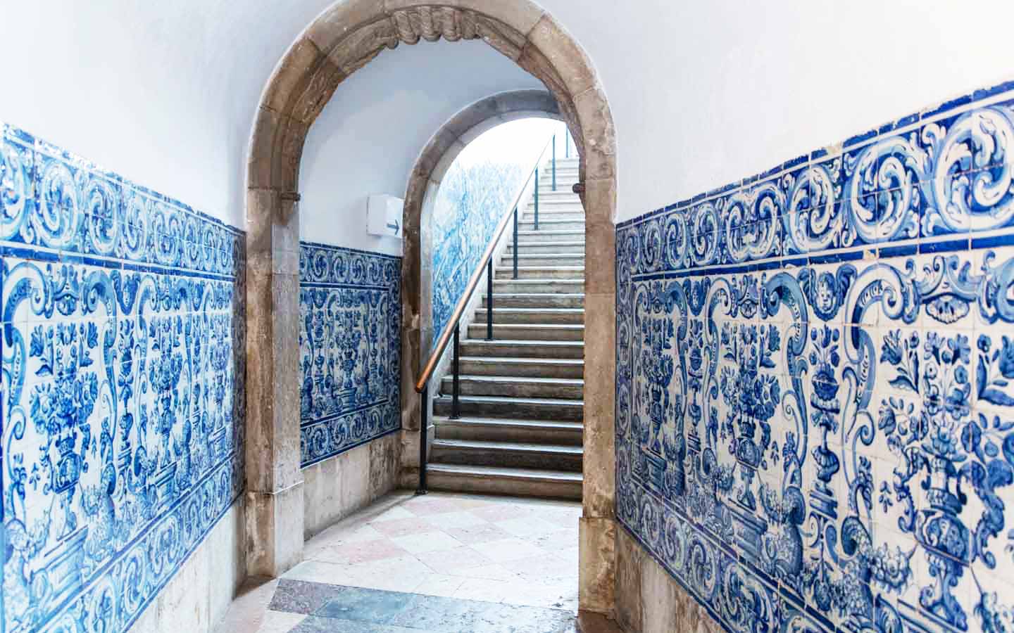 Blue and white glazed wall tiles forming a panel next to a stone staircase.