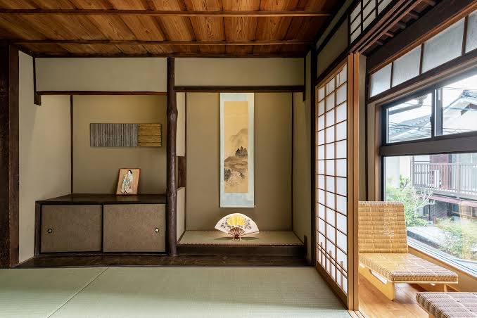 A recessed alcove in a tatami room with a hanging scroll above a low vessel.